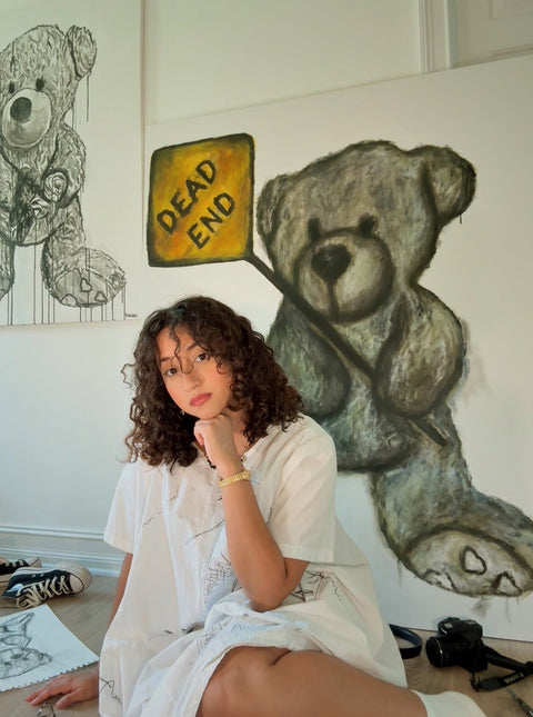 Person sitting in front of a wall with teddy bear drawings and a 'DEAD END' sign.