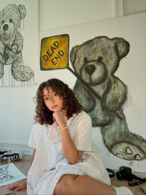 Person sitting in front of wall with teddy bear drawings and 'DEAD END' sign